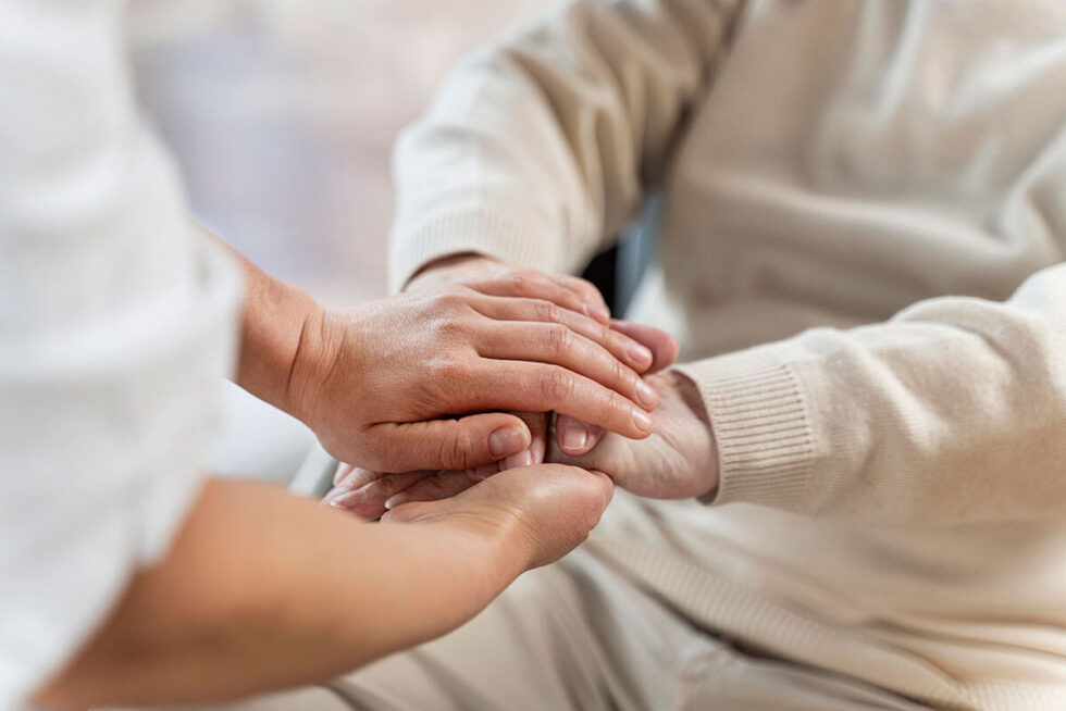 Nurse holing hands with senior patient